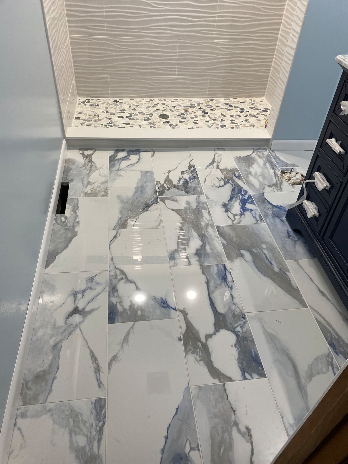 Marble-look floor tile with pebble-tile shower base