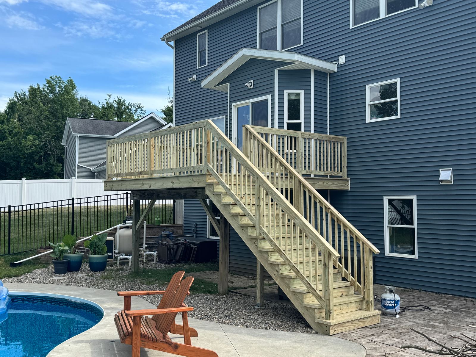 Second-story pressure-treated deck with a full stair run beside an in-ground pool