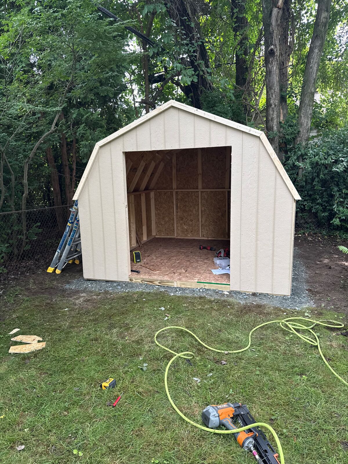 Gambrel-style shed with siding on and door opening framed