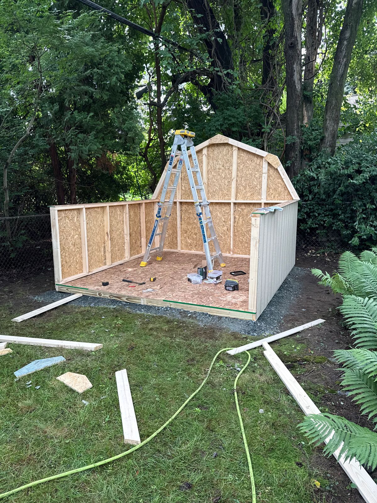 Gambrel-style shed walls going up on a gravel pad